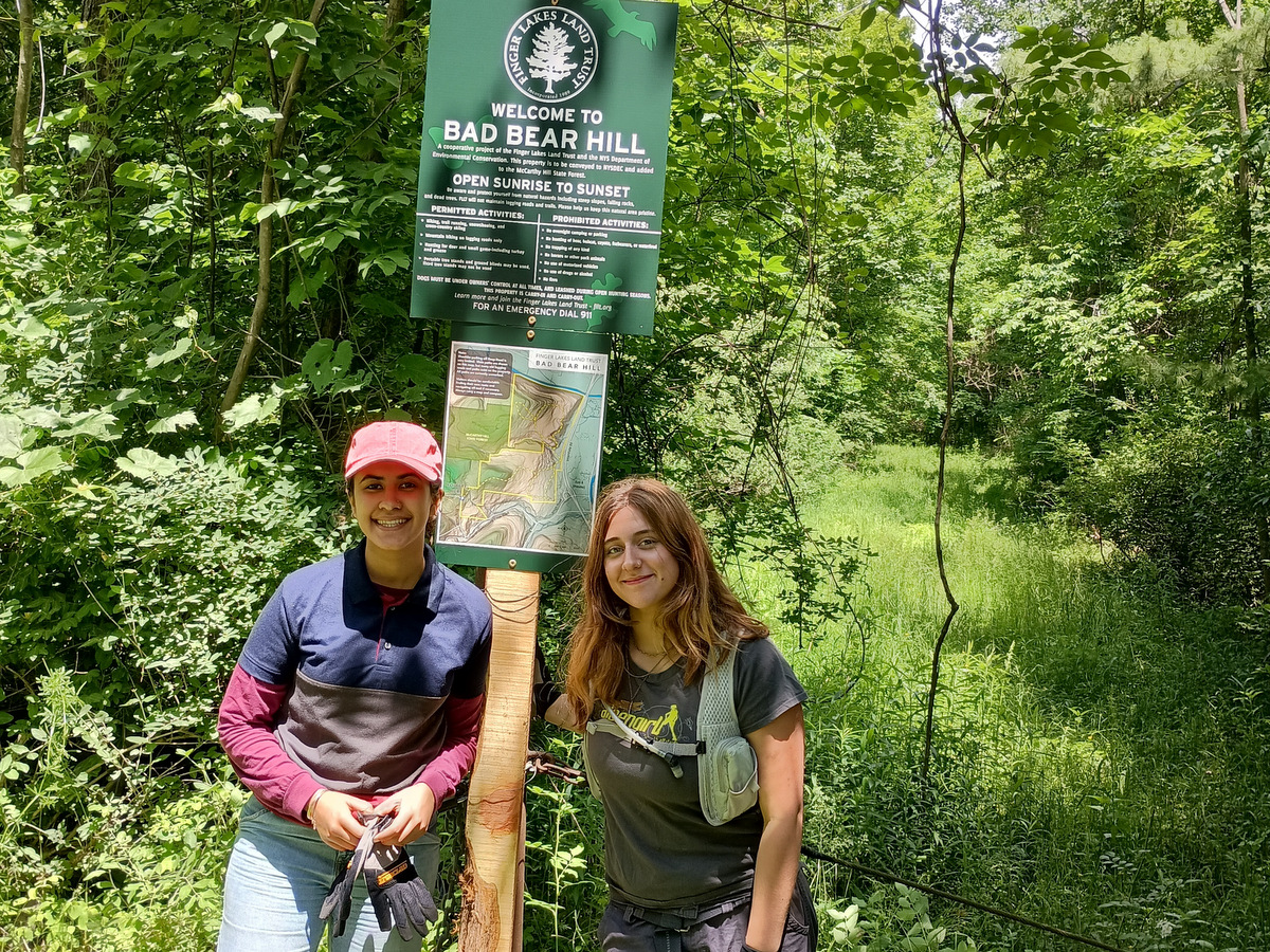 Two people standing next to a trail sign